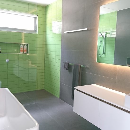 Bathroom design, contemporary bathroom, subway tiles, green subway tiles, feature tiles, floating vanity, custom joinery, backlit mirror, countertop basin, back to wall bath, shower niche