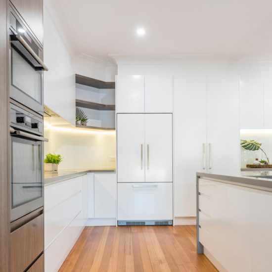 Kitchen design, contemporary kitchen, woodgrain laminate, stone benchtops, waterfall edge, white kitchen, glass splashback, white splashback, integrated fridge