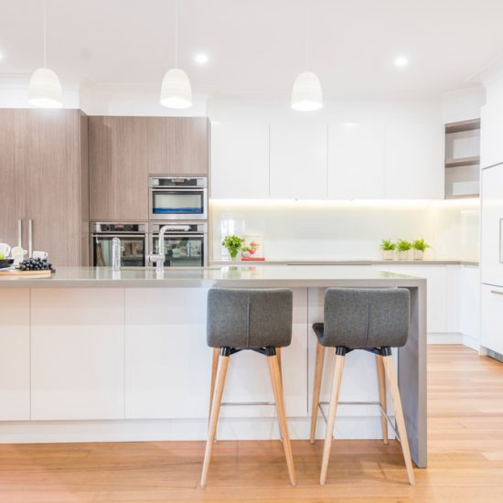 Kitchen design, contemporary kitchen, woodgrain laminate, stone benchtops, waterfall edge, lighting over island, white kitchen, glass splashback, white splashback, integrated fridge, push close doors, handle-free