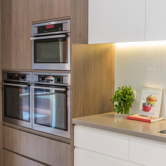 Kitchen design, contemporary kitchen, woodgrain laminate, stone benchtops, white kitchen, glass splashback, white splashback, push close doors, handle-free