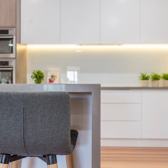 Kitchen design, contemporary kitchen, woodgrain laminate, stone benchtops, waterfall edge, white kitchen, glass splashback, white splashback, push close doors, handle-free