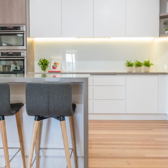 Kitchen design, contemporary kitchen, woodgrain laminate, stone benchtops, waterfall edge, white kitchen, glass splashback, white splashback, push close doors, handle-free